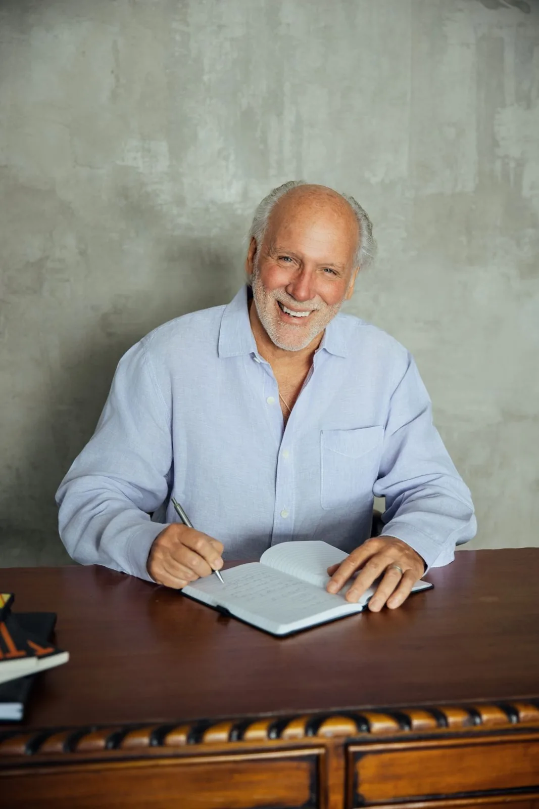 Dennis smiling at a writing desk, pen in hand