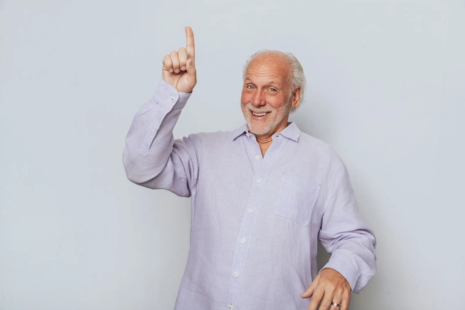 Dennis smiling, one finger raised